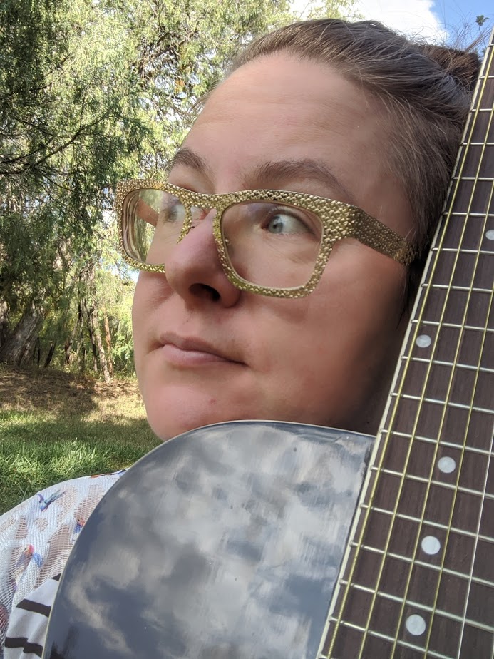 Tara holding a guitar outside.