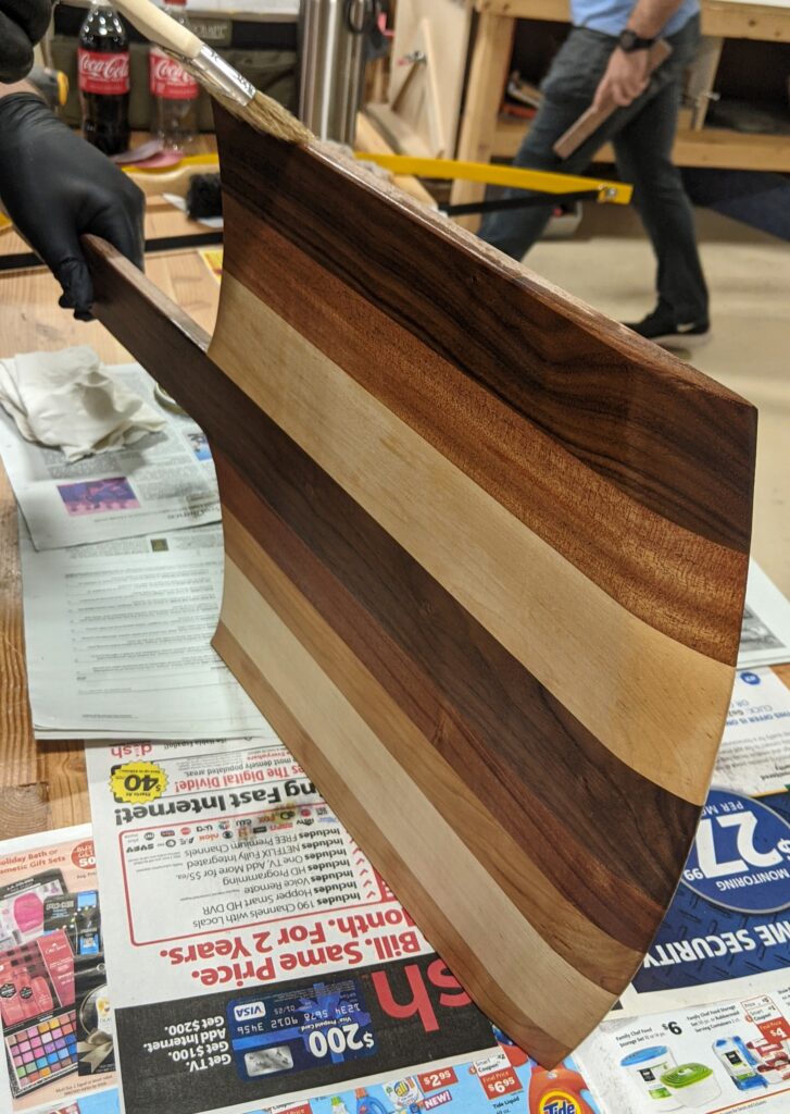 A brush applying linseed oil to the pizza peel. 