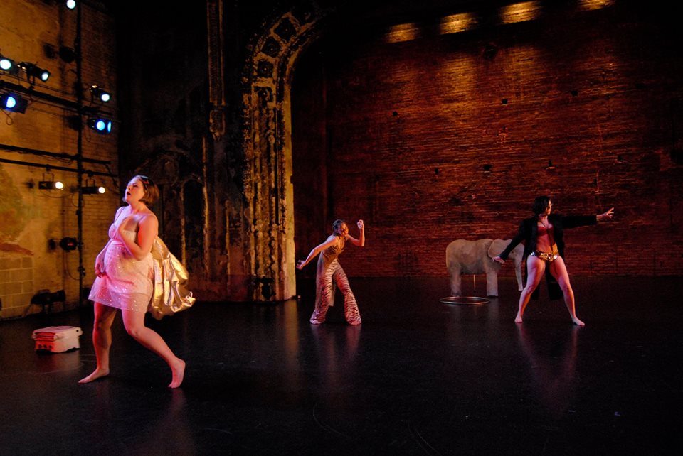 A large stage made of bricks, with three people dancing on it -- one of them is me. There's also a small elephant in the back. 