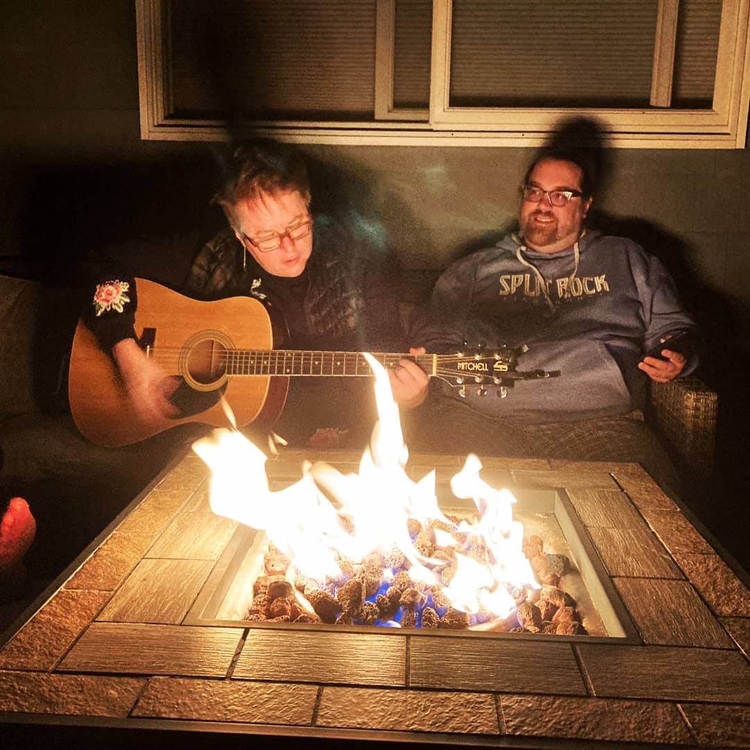 Tara playing guitar by a fire.