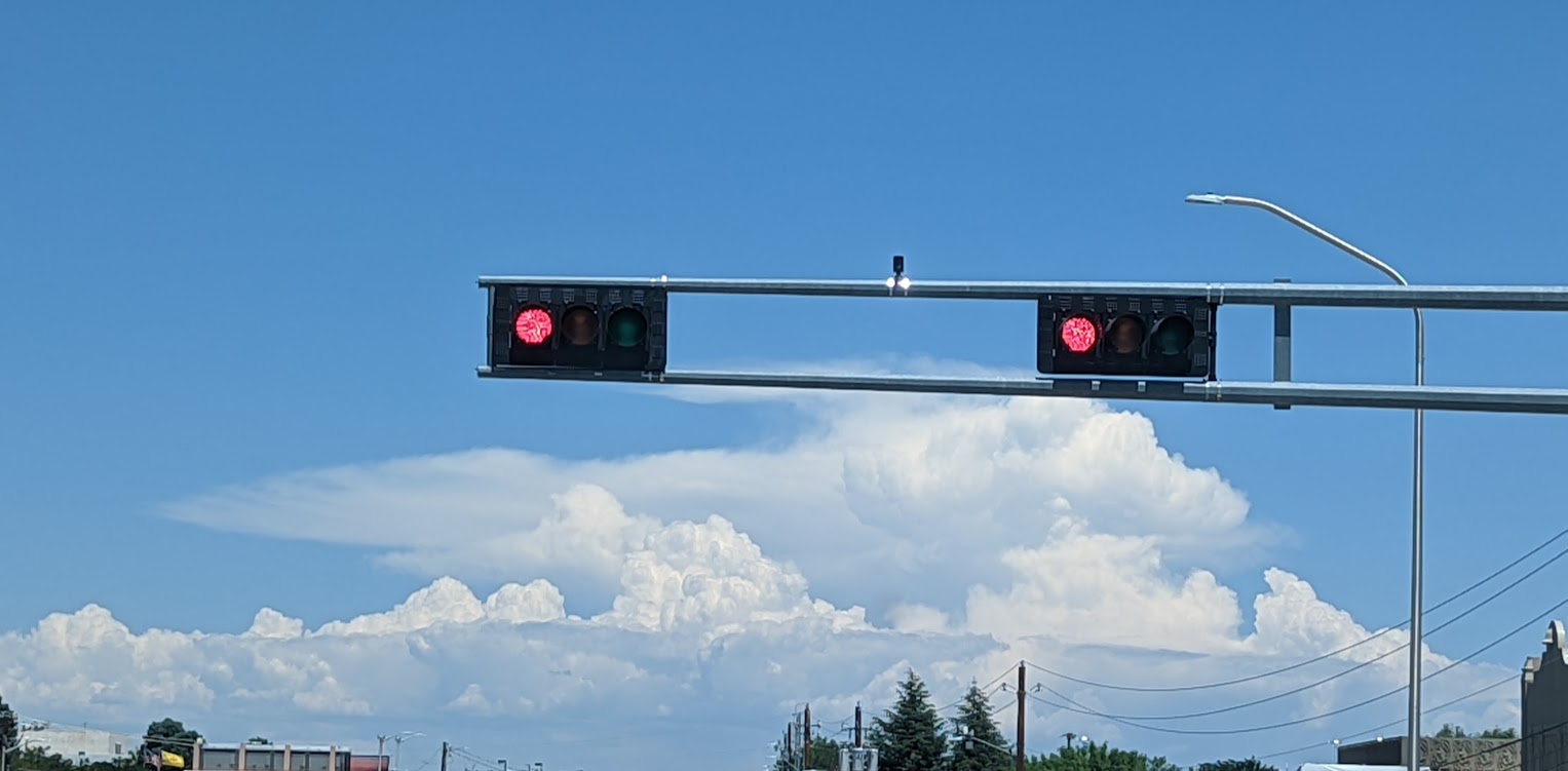 Red traffic light that looks like two eyes above a mouth made of clouds.